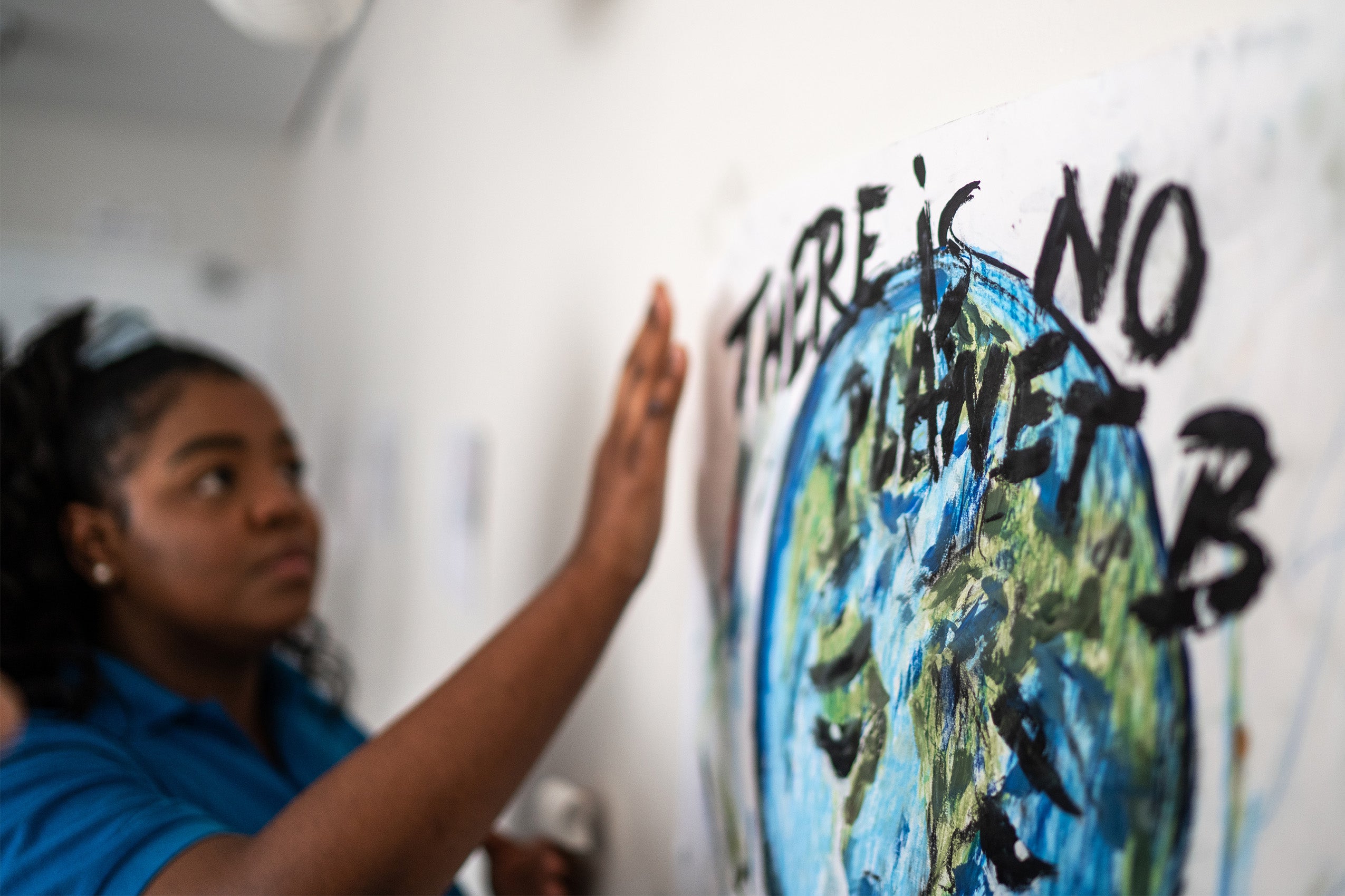 Student fixing in the wall a poster about environmental issues - There is no planet B