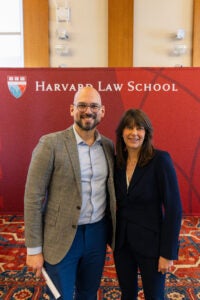 Two people pose in front of backdrop.